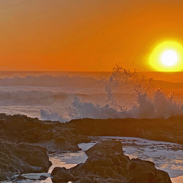 Sunset at Yachats. Waves crash into the rocks and spray catches the golden light of the setting sun.