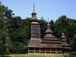 A small wooden church with three wooden spires.