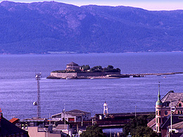 A tiny prison island in the distance with mountains far away across the water