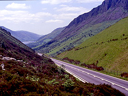 A valley with steep sides, with a two-lane road passing through.