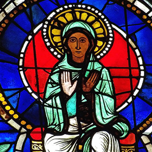 Mary sits and faces the viewer, holding both her hands up with palms facing us.  She is brown and so is her left hand, but her right hand is white
