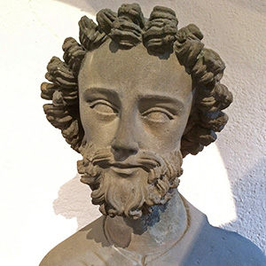 A stone statue showing a holy man with curly hair. 
