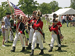 Fife and drum players marching through encampment.