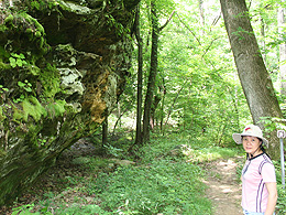 Jeri standing on a trail near a wall of moss covered rocks