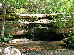 water dripping down a rock face into a pool.