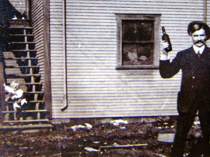 A little boy sits on some steps, and a man holds a bottle and poses for the camera