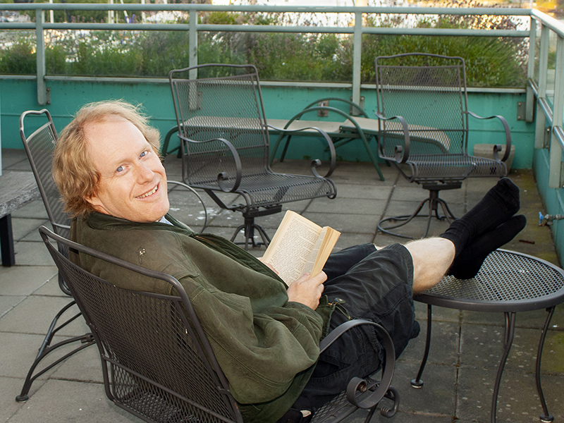 Eric sitting and reading a book in the cool Vancouver Air (he is wearing a coat and shorts)