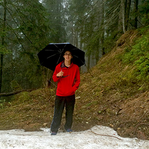 Arthur stands in a forest in front of some snow