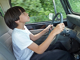 Arthur driving a car down a farm road