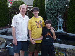 Eric standing with his sons Sebastian and Arthur in front of a pool of water