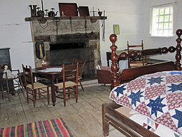A bed, a fireplace, a table with four chairs, a rug on the wooden floor