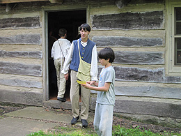 Two boys standing outside a log home.