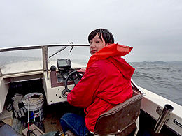 Sebastian is steering the boat in the rough open water.