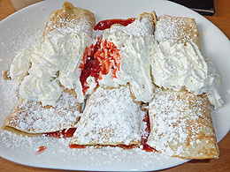 Strawberry crepes with powdered sugar and whipped cream.