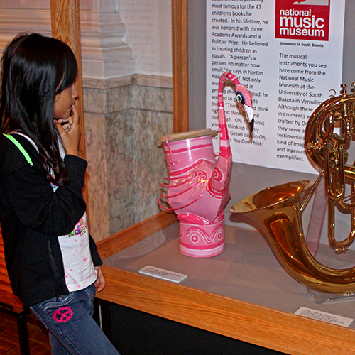 Small girl looks at unusual horn instruments.