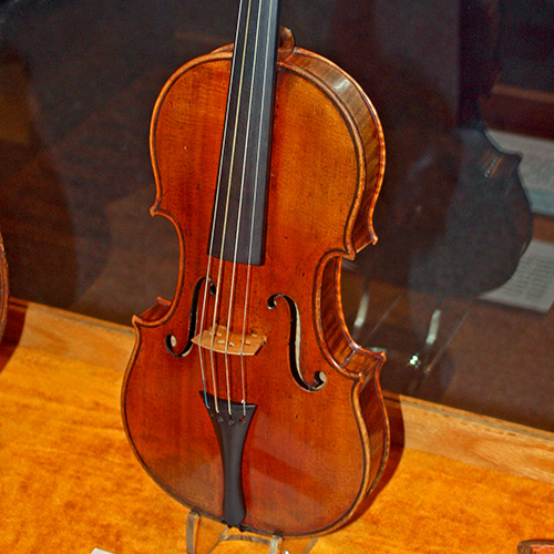 An old violin stands in a case on display.