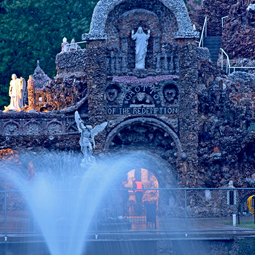 Fountain in the dim light of evening on a rainy night with the grotto behind it