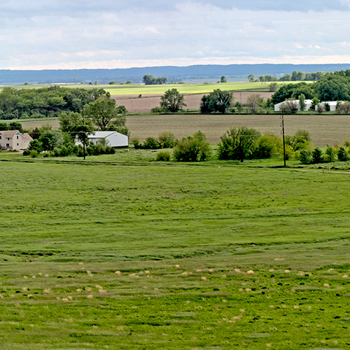 Flat fields and grasslands with scattered homes and trees