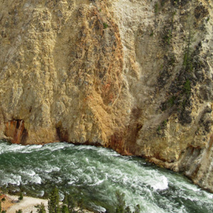Yellow and orange and pale beige stones down to the green Yellowstone River