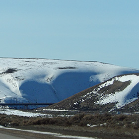 Soft snowy drifts rise up behind US--30 highway