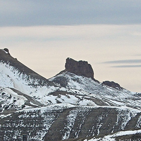 A rocky outcrop rises out of a snow-covered hill.