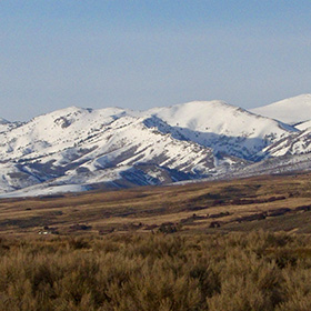 Snow-covered mountains rise above sagebrush