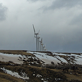 Wind turbines loom above a snowy ridge