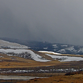 A small shaft of light penetrates the dark clouds of snow and ice on the Medicine Bow foothills.