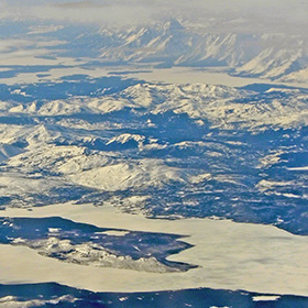 A view from a plane window of Lake Yellowstone (frozen over) and in the distance, the Tetons