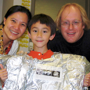 Eric and Jeri on either side of Arthur in his first grade classroom.  Arthur is wearing a dust costume.