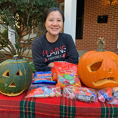 Two pumpkins on a table with some candy, and Jeri is smiling behind the table