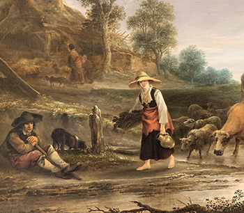 A woman with a broad straw hat walks barefoot along a muddy road as cattle and sheep follow on the road behind her.