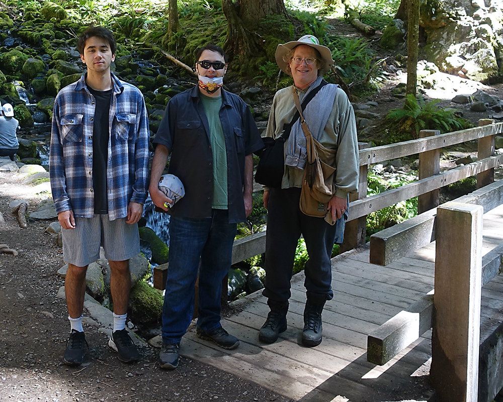 The Hadley-Ives men stand on the bridge over a rocky stream