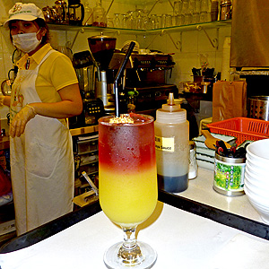 Glass full of sweet, fruity drink with yellow color at the bottom of the glass and red color at the top of the glass