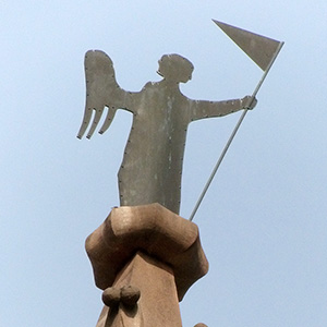 Statue inside the cathedral with stained glass behind it