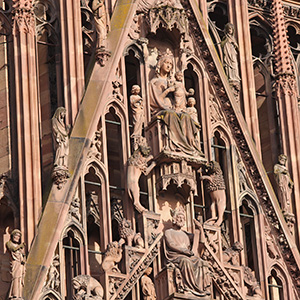 Jessu hangs on the cross, with his eyes shut. On either side of him stand figures who are in great distress.