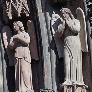 Jesus sits in the center of the table with his left arm resting on the shoulder of one disciple, while, with his right arm, he feeds another disciple who is crouched in front of the table. 