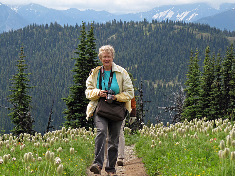 Mom walks on the trail through a meadow covered in pasqueflower