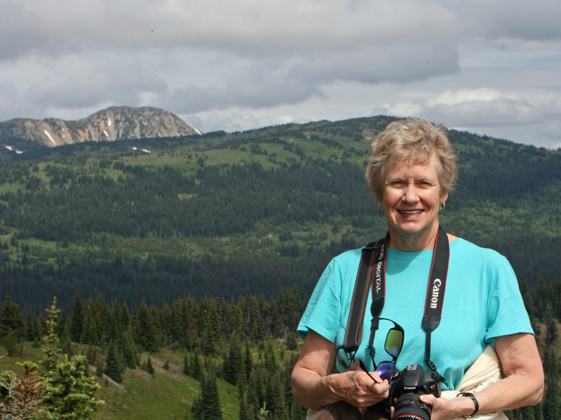 Close up of my mom squinting into the sun with Big Buck Mountain in the distance behind her