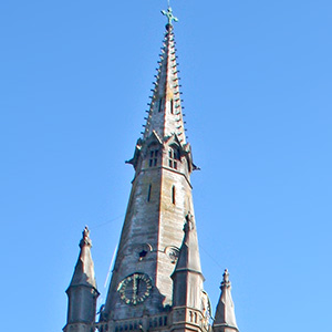 Golden spire on the Basel town hall with dark clouds behind it.