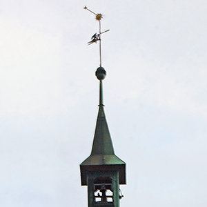 Golden spire on the Basel town hall with dark clouds behind it.