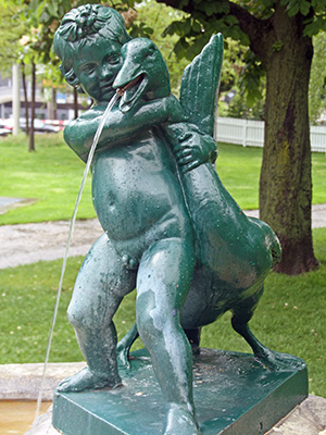 Boy struggling with goose water fountain in park in Basel. 