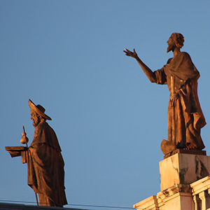 Two lions of stone, with one reaching with its paw toward the other lion.