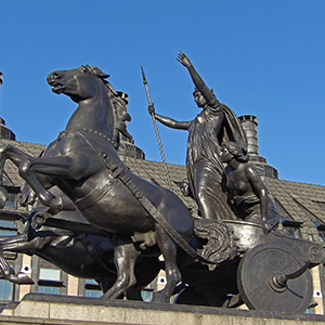 Two lions of stone, with one reaching with its paw toward the other lion.