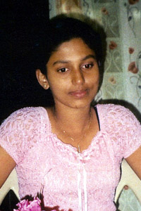 Nadeeka in a pink dress sitting at a table with a flower